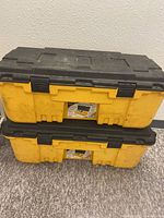 Two yellow XXL Plano storage boxes stacked, showing front and side views with visible wear and latches.