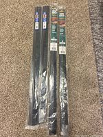 Four new door sweeps in plastic packaging laid on carpet. Two branded M-D Building Products commercial sweeps, and two labeled 3 inch door sweeps.
