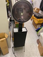 Full view of Apollo hair dryer showing large hood and base with legs, placed in storage area.