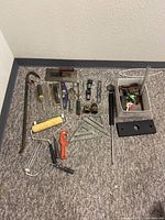 Overhead view of the assorted hand tools arranged on carpeted floor.