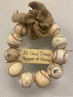 Full wreath of 10 used baseballs with burlap bow and wooden sign on wall