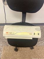 Top view of GBC DocuSeal 125 laminate machine on a black chair, showing front branding and control panel.