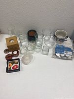 Multiple glass candle holders of varying shapes and sizes arranged together with other decorative candle holders and a pack of tealight candles.