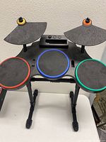 Full front view of the Guitar Hero Wii drum set showing all 4 drum pads and 2 cymbals on the black adjustable stand.