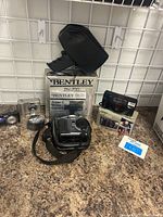 Photo of lot showing Bentley BV-720 Super 8 movie camera with black carrying case, silver Canon point-and-shoot, and Kodak DC290 Zoom camera in case.