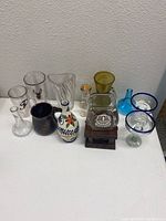Top view of eleven assorted glass and ceramic items on a flat surface against white background showing variety in color and form