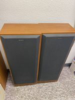 Pair of Sony bookshelf speakers side by side with black fabric grills on.