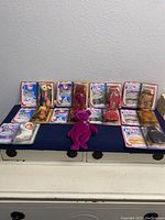 Full lot of 11 TY Beanie Babies including 10 in original packaging and one loose purple Millennial Bear plush toy.