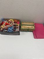 Photo showing a box with floral fabric and sewing supplies, a green-accented wicker sewing basket, and bright pink fabric on the side.
