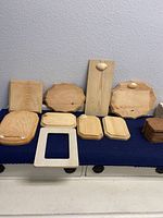 Top view of entire lot showing various wooden plaques and stacked bread coasters on a blue cloth surface.