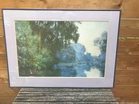 Front view of framed art print showing landscape scene with river and trees.