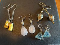 Four pairs of earrings on dark surface showing all designs and styles