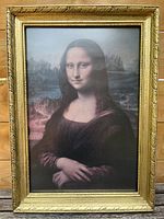 Front view of the framed tempered glass print of The Mona Lisa, showing the gold ornate frame and the print behind glass.