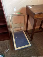 Metal platform cart with blue plastic top surface and beige foldable handle, showing damage to top surface.