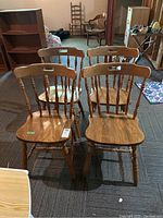 Four wooden chairs arranged in square formation showing front and seat details.