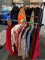 Overview of jackets and clothing hanging on rack showing variety of mens and womens jackets including safety jacket and animal print jacket