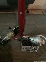 Kenmore Stratus 14.4V electric broom in red upright style, Bissell pet hair hand vacuum in black and green, Shark silver hand vacuum with box and cords visible.
