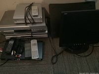 Acer 17-inch monitor, Toshiba and Pioneer DVD players with remotes, cables on floor.