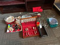 Overview of kitchenware assortment including cutlery box, baking dishes, glasses, BBQ tools, trays and others