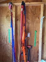 Photo of multiple ratchet straps hanging on a wooden wall, showing different colors and hooks.