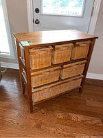 Front view of the wood cabinet showing six woven baskets with leather pull handles arranged in two rows.