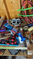 Overview of multiple screwdrivers, pliers, tape rolls, and other hand tools on a wooden surface with coiled cords in background.