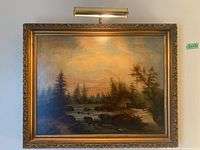 Full view of large framed landscape print with ornate gold frame and light fixture illuminating the artwork
