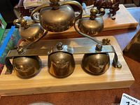 Front view of three brass horse carriage bells mounted on a wooden slat, polished with mounting hardware visible