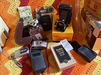 Vintage Kodak Vigilant Junior folding bellows camera in black with original box and leather case, cardboard Kodak Kodak Tourist guide, and other cameras.