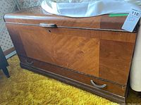 Front angled view of wooden cedar chest showing parquet pattern and drawer with metal handles