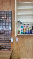 Photo of two hardware organizers filled with assorted screws, bolts, nails, and small hardware pieces adjacent to a wall shelf with lubricating oils and tools