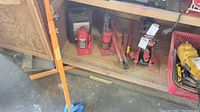 Shelf with several hydraulic bottle jacks, honey orange hydraulic floor jack and hydraulic jack fluid container