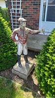 Front view of the cement lawn jockey statue positioned outdoors near a house wall.