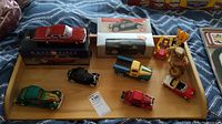 Full view of wooden tray with seven model cars and three wind-up vintage toys.