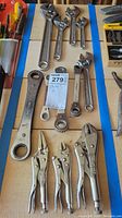 Overview of lot on table showing adjustable wrenches and locking pliers organized on cardboard.