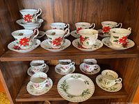 Two shelves displaying multiple Royal Albert teacup and saucer sets in three patterns plus serving plate.