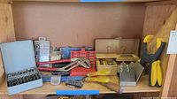 Full shelf view showing various tools including drill bit boxes, clamp, hand tools and wrench