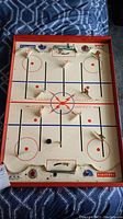 Full overhead view of the vintage electric hockey table game showing metal players, puck, and rink layout