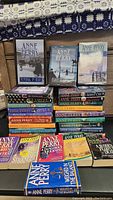 Photo showing a selection of Anne Perry books, including Funeral in Blue, Slaves of Obsession, and The Shifting Tide, arranged on a surface.