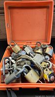 Full view of orange case holding various metal padlocks and keys