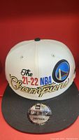 Front view of the hat showing white crown, gray brim, embroidered Golden State Warriors logo and 21-22 NBA champions text.