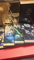 Photo showing the opened Star Wars Trilogy DVD set with 4 individual movie cases and accompanying booklet, all with detailed Star Wars themed cover art.
