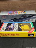 Photo showing boxed Stress Relief Train and Beam & Read Mini Reading Light boxes stacked horizontally.