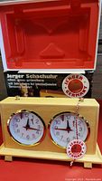 Photo of the Jerger chess clock inside the original box showing the clock front and red interior box mold.