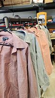 Photo of 6 Lands' End long-sleeve men shirts hanging on hangers in multiple pastel colors.
