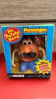 Front view of boxed Mr. Potato Head massager showing colorful packaging and product inside.