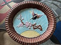 Full top-view of oval Majolica ceramic plate featuring bird and cherry blossom design with textured turquoise and brown border.