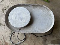 Top view of pottery wheel with plaster bat showing worn surface and electrical cord.
