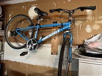 Side view of blue Diamondback bike mounted on wall showing frame, wheels, drivetrain and brakes