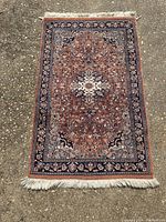 Front of the Persian rug showing rust red field with intricate floral and medallion pattern, blue and ivory accents, and cream fringes.